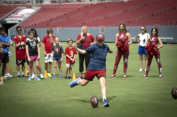 A young boy winds up to kick a football